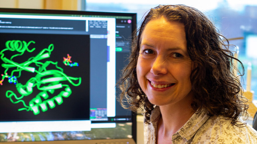 Smiling woman in front of computer monitor with graphic pattern