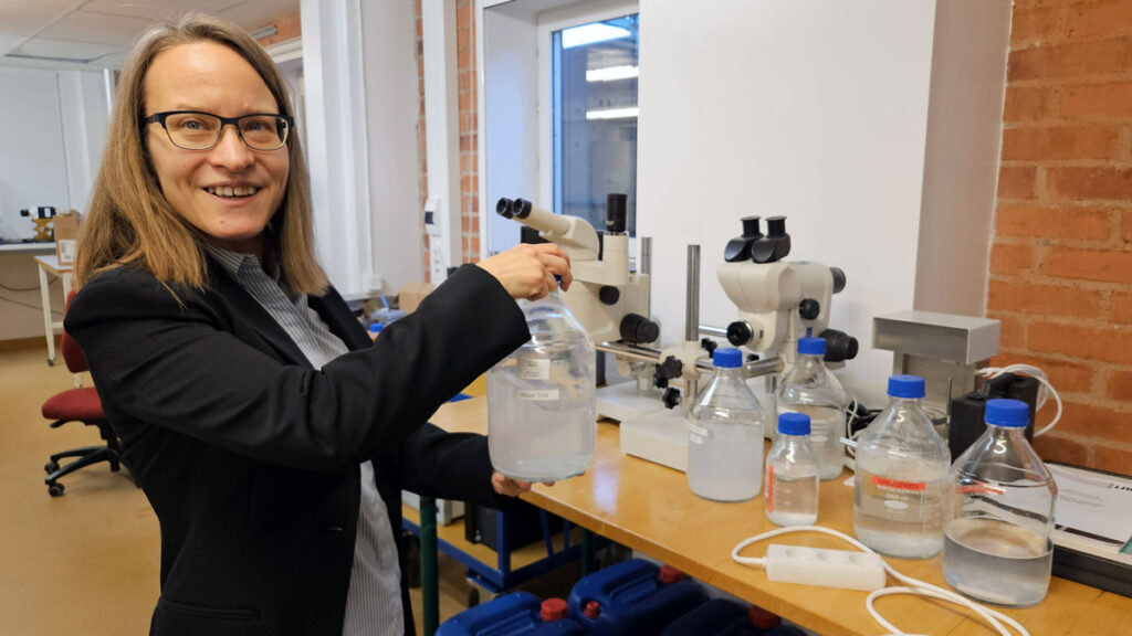 Woman holding bottle in chemical wet lab