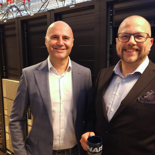 Two men in suits in front of computer racks