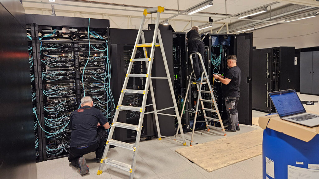 Technicians installing supercomputer with ladders and laptop