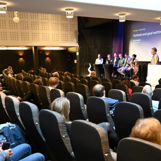Audience in conference room listening to people on stage