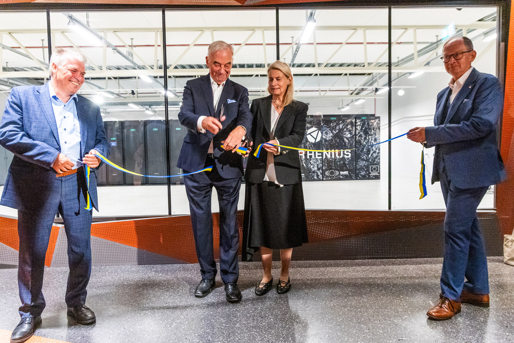 Smiling people cutting ribbon in front of supercomputer